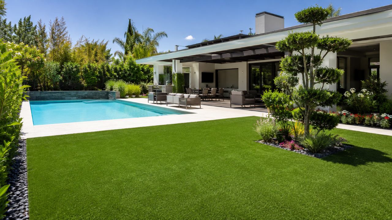 Gazon synthétique impeccable autour d'une terrasse et d'une piscine dans un jardin soigné → Piscine et Jardin