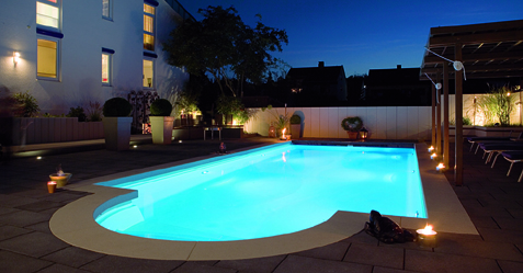 Piscine romane extérieure éclairée dans la soirée